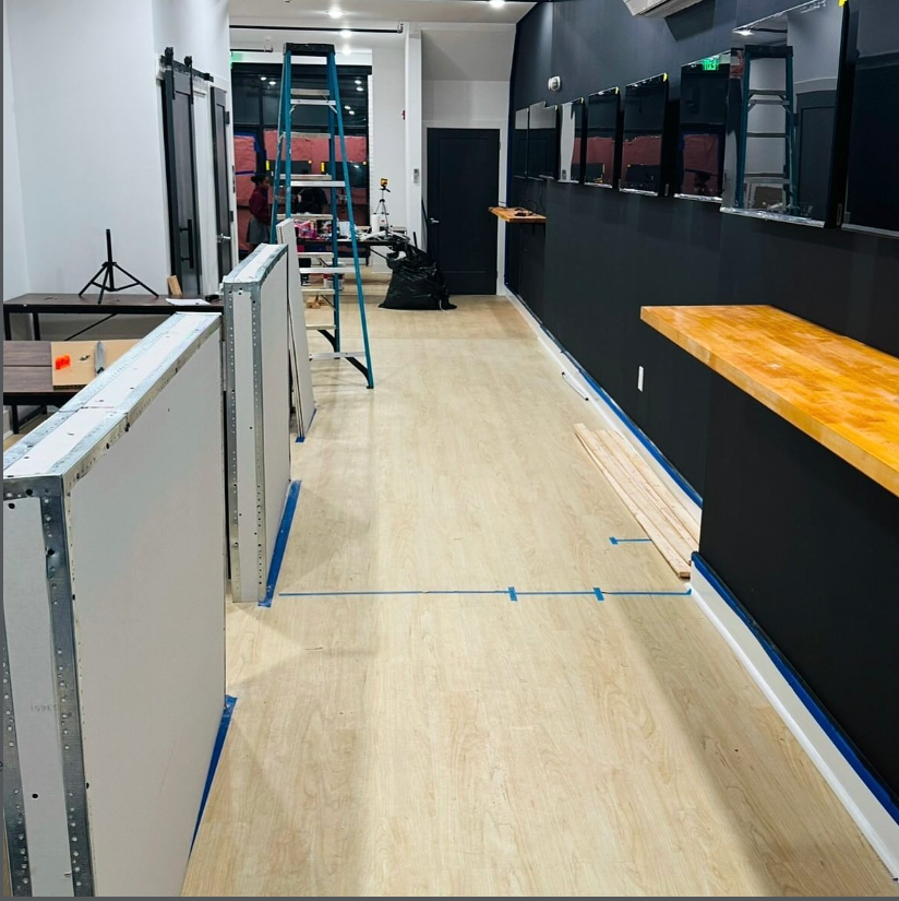 Open World Gaming Center interior under construction with ladder, unfinished counter, and monitors being installed