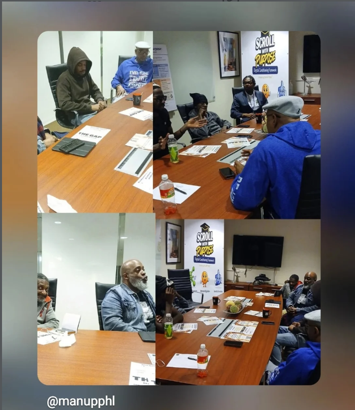 A ManUpPHL session in North Philadelphia with mentors and community members around a conference table and the Scroll With Purpose banner in the room